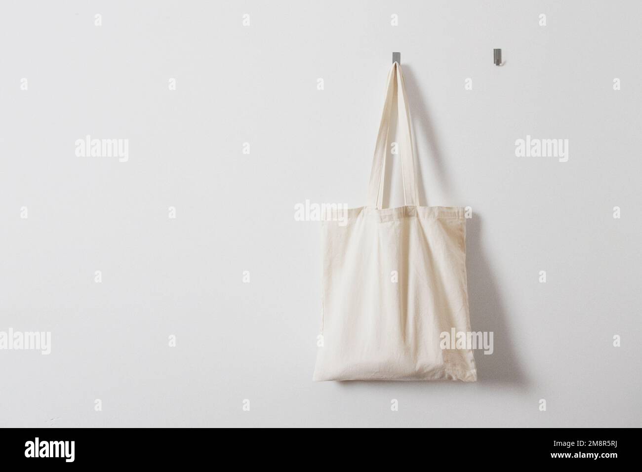 Sac de chiffon blanc pour les articles d'épicerie. Sac réutilisable. Végétarisme, régime alimentaire brut, consommation consciente, tissu. Sac en tissu blanc suspendu sur un crochet Banque D'Images