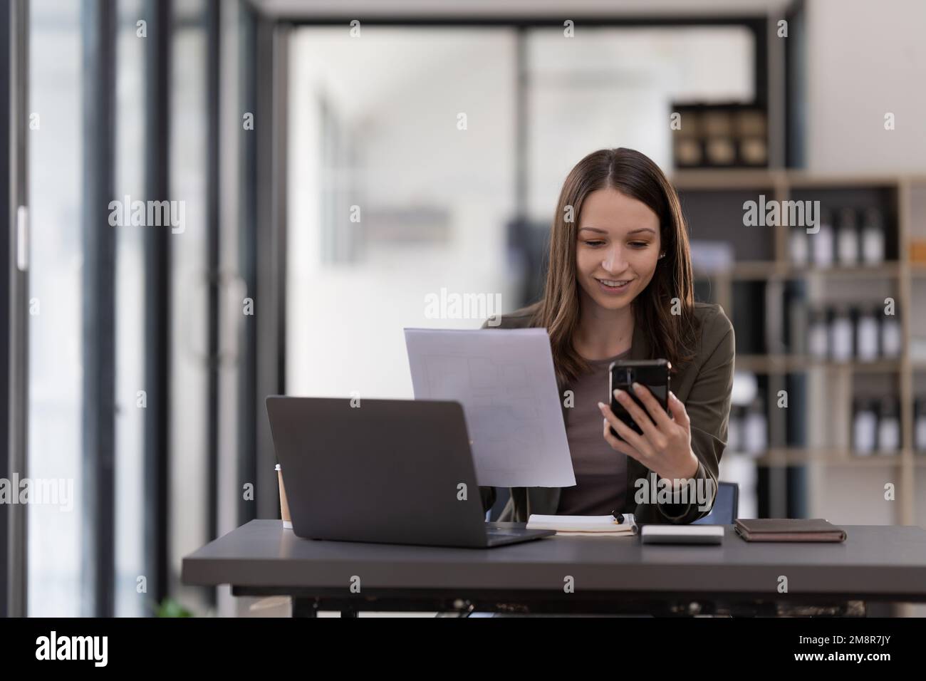 Femme d'affaires utilisant un smartphone pour faire des finances mathématiques sur un bureau en bois dans le bureau, la fiscalité, la comptabilité, le concept financier. Banque D'Images