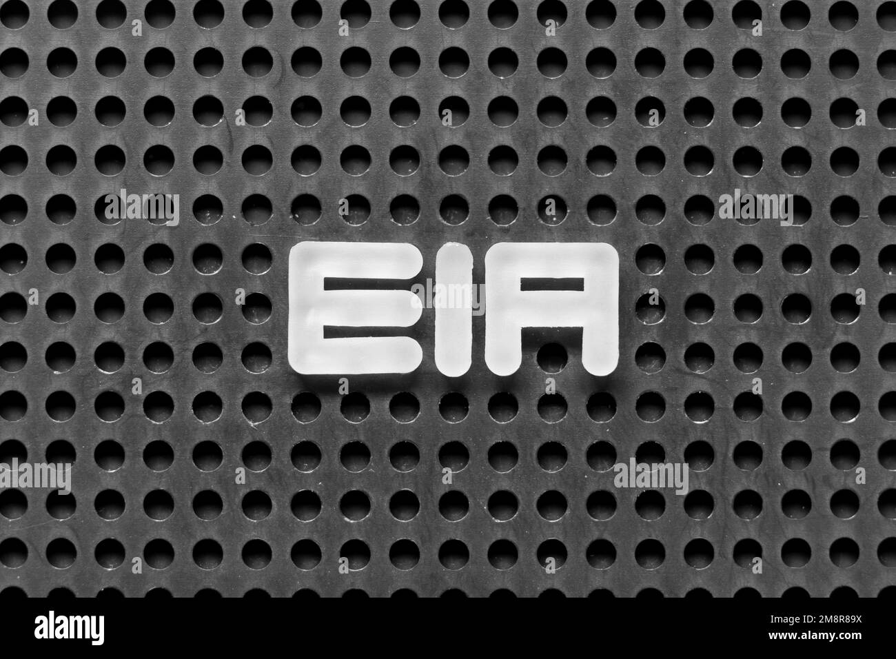 Lettre en alphabet blanc dans le mot EIA (abréviation de Environmental impact Assessment) sur fond perforé noir Banque D'Images