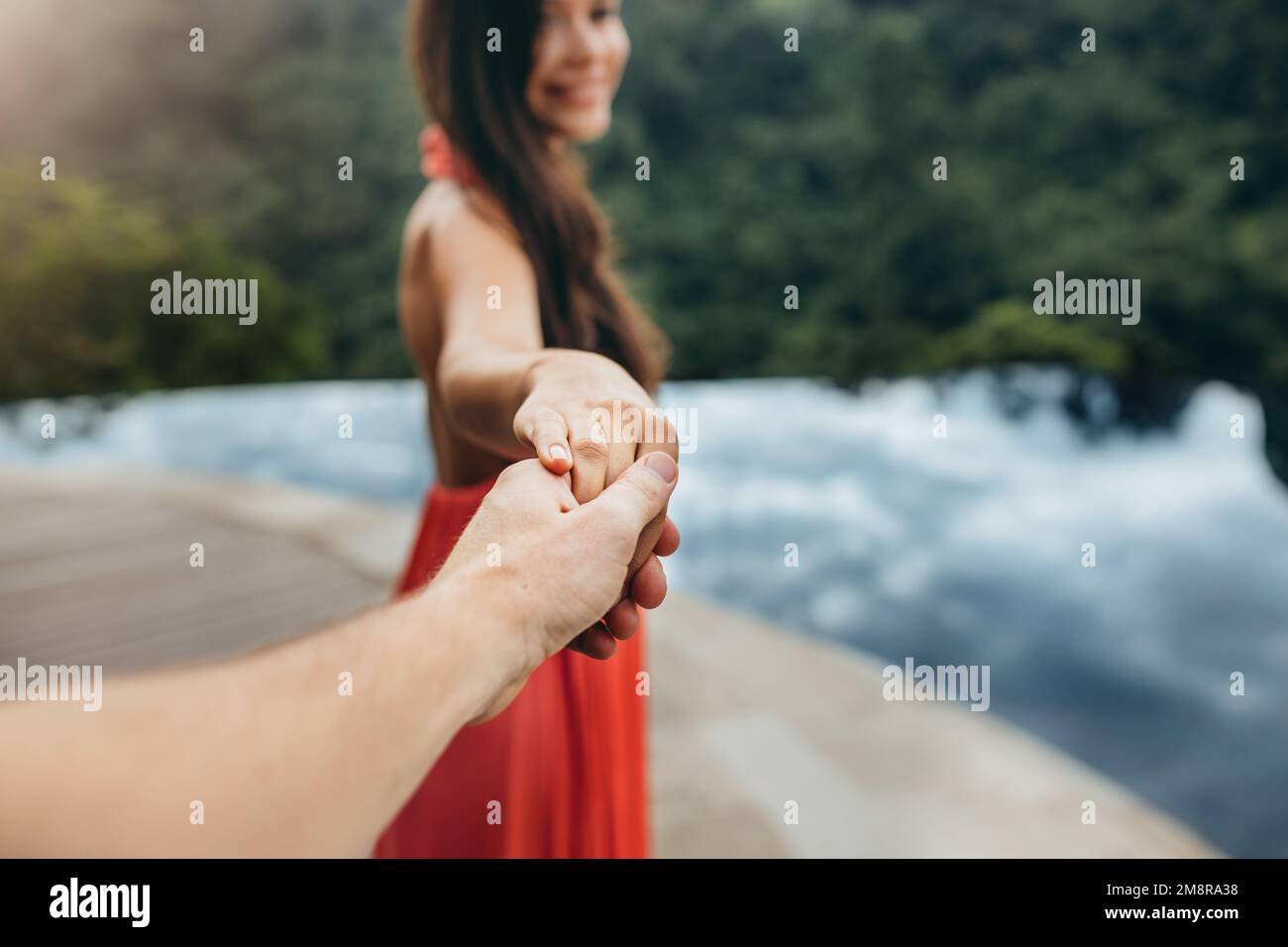 Gros plan d'une femme tenant la main d'un homme près de la piscine. Concentrez-vous sur les mains du couple. Prise de vue POV. Banque D'Images