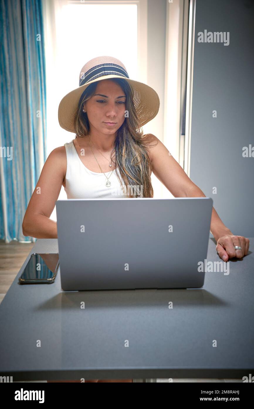 Photo verticale d'une femme d'affaires dans un chapeau à large bord qui travaille et regarde l'écran d'un ordinateur portable Banque D'Images