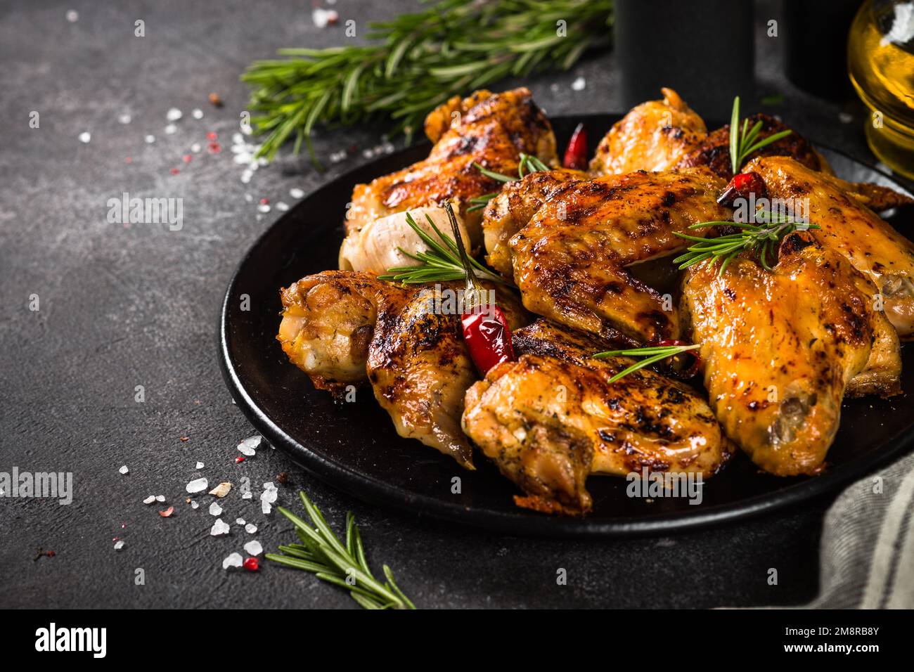 Ailes de poulet grillées aux épices et à la sauce tomate sur une table de cuisine noire. Banque D'Images