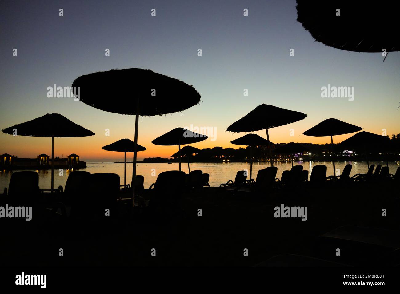 Plage sur la mer Méditerranée dans la Reviera turque. Côte au coucher du soleil avec parasols près d'Alanya en Turquie. Banque D'Images