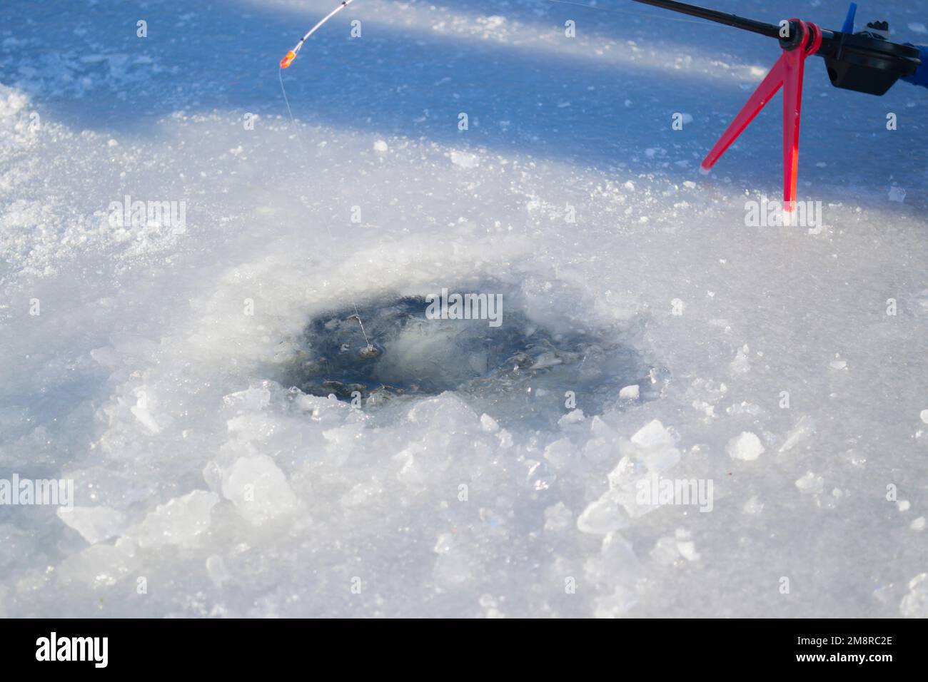 Pêche sous la glace en hiver. Pêche sous la glace en hiver. Une petite canne à pêche se trouve près d'un trou dans la glace d'une rivière par beau temps. En hiver Banque D'Images