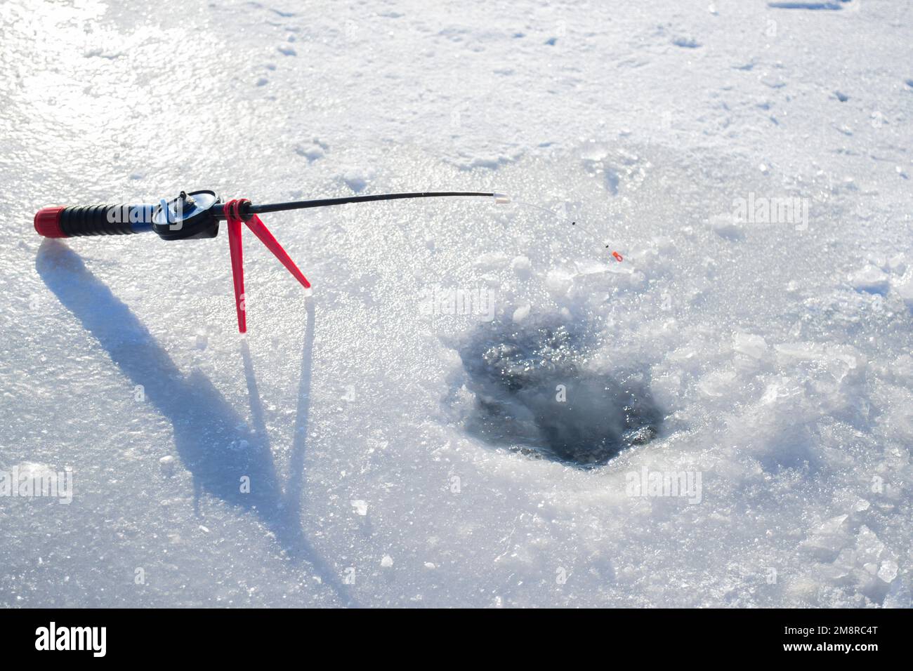 Pêche sous la glace en hiver. Pêche sous la glace en hiver. Une petite canne à pêche se trouve près d'un trou dans la glace d'une rivière par beau temps. En hiver Banque D'Images