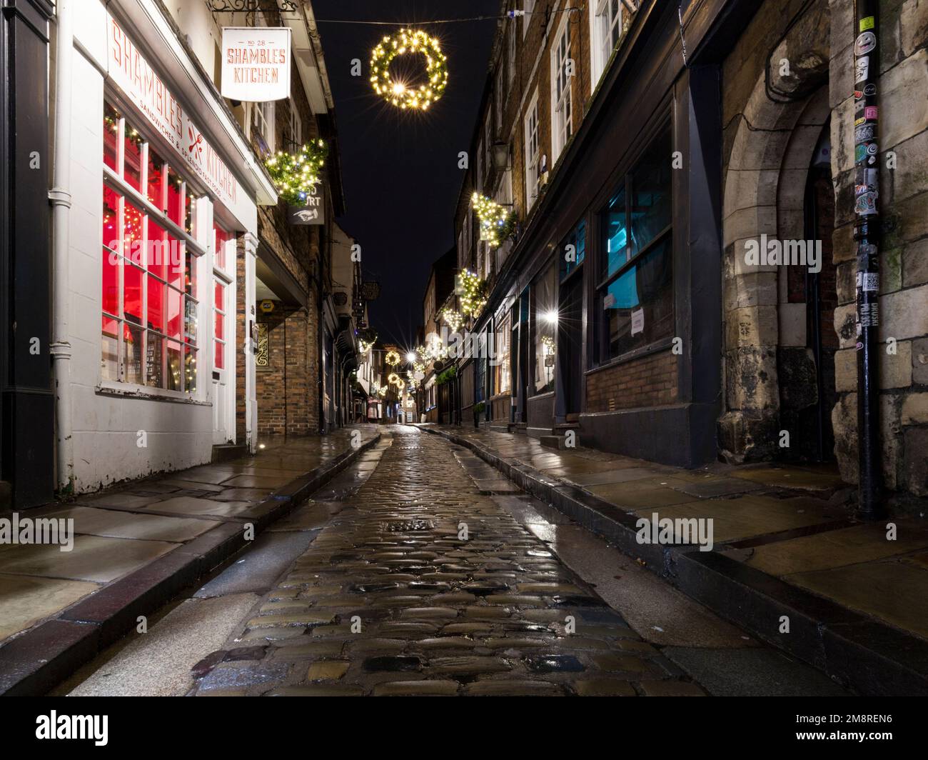 Les ruines, rue médiévale historique à York à l'heure de Noël avec rue pavée humide Banque D'Images
