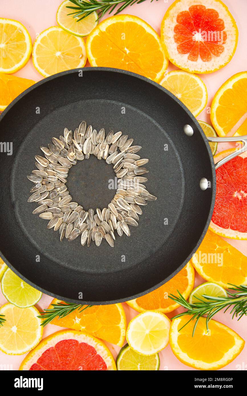 fond de tranches d'agrumes, oranges, citrons, limes, pamplemousses, sur lequel est placé une casserole noire, à l'intérieur de laquelle est faite une fleur de tournesol fr Banque D'Images