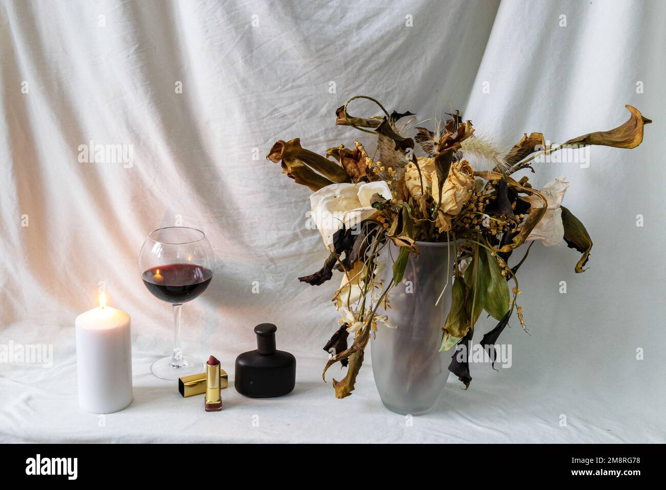 photo de la vie avec de belles fleurs colorées sèches dans un vase, accessoires cosmétiques, fond en tissu blanc Banque D'Images