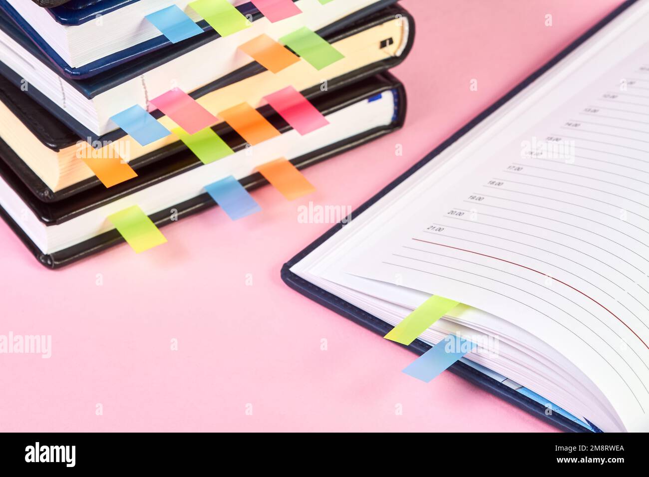 Gros plan d'un bloc-notes ouvert avec des marqueurs de page adhésifs colorés sur l'arrière-plan d'une pile de blocs-notes de bureau Banque D'Images