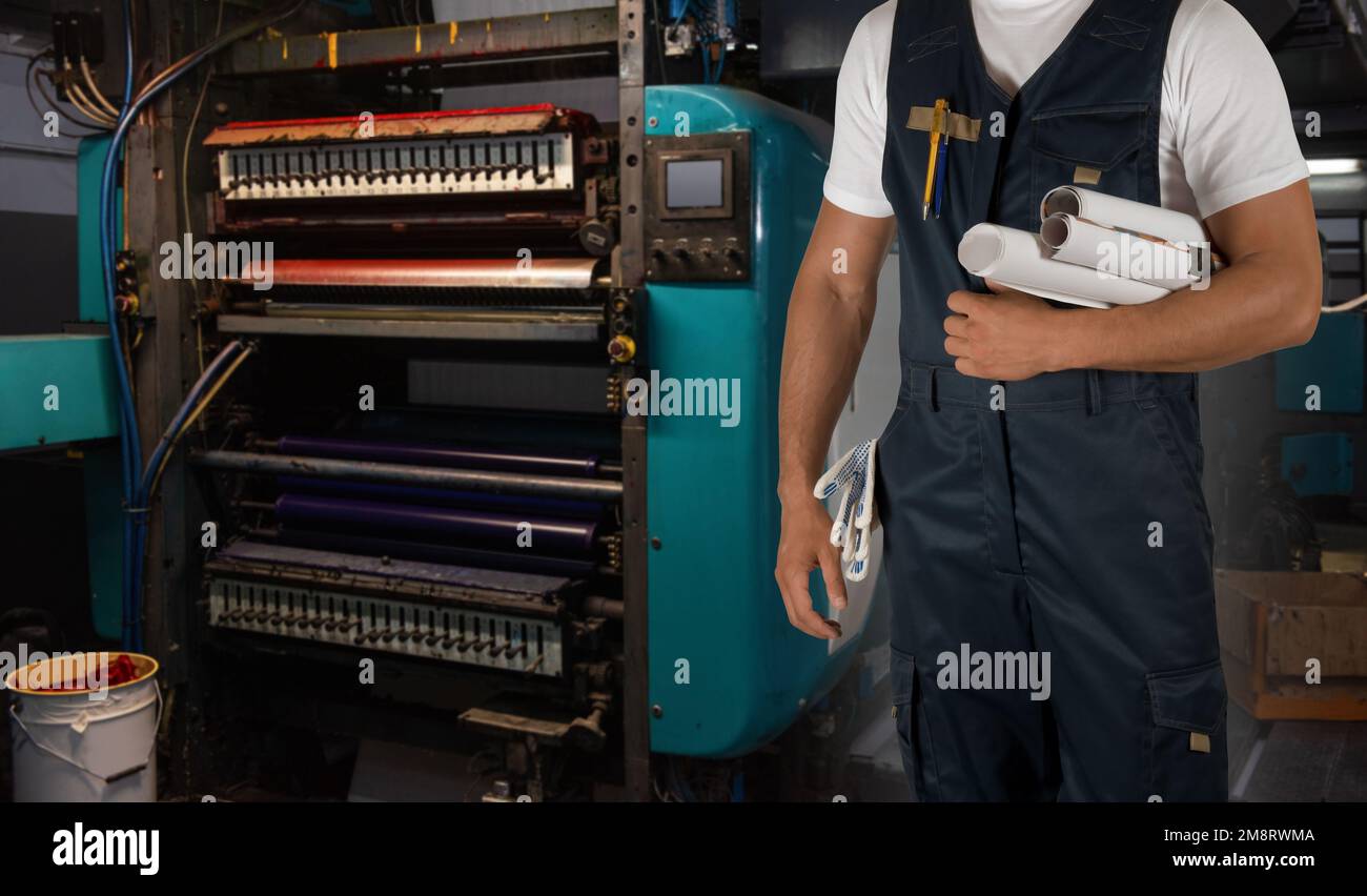 Homme travaillant dans une imprimerie avec du papier et une machine à imprimer Banque D'Images