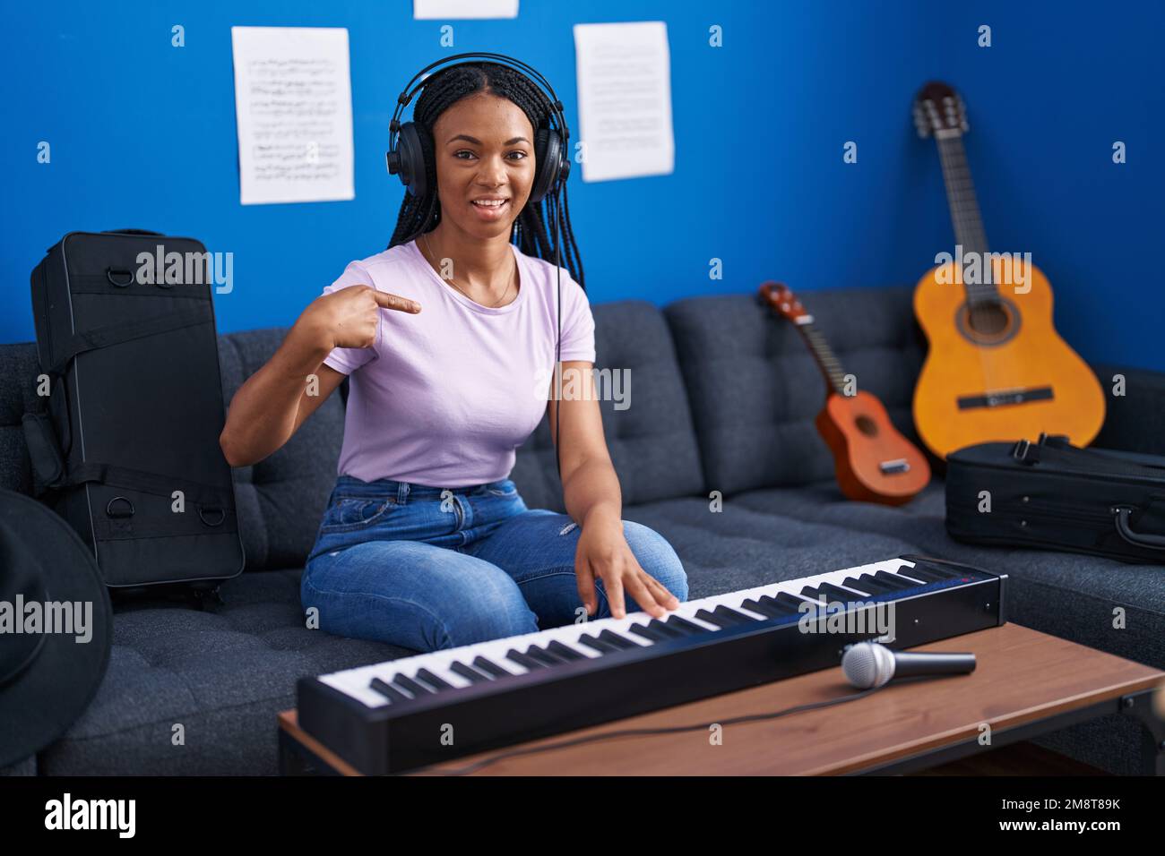 Femme afro-américaine avec des tresses jouant le clavier de piano dans un  studio de musique pointant du doigt vers un soi souriant heureux et fier  Photo Stock - Alamy