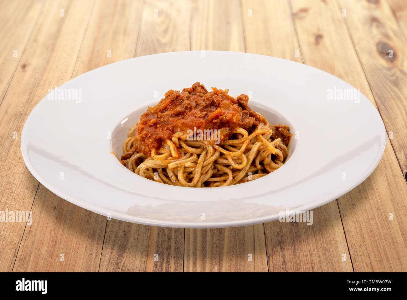 Tajarin piémontais, tagliolini italien (nouilles) à base de pâtes à la farine, d'œufs et de truffes, nappés de sauce tomate et à la viande dans une assiette blanche sur bois Banque D'Images