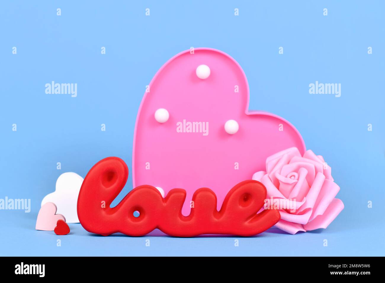 Décoration de Saint-Valentin avec mot rouge amour, roses et ornements coeur sur fond bleu Banque D'Images