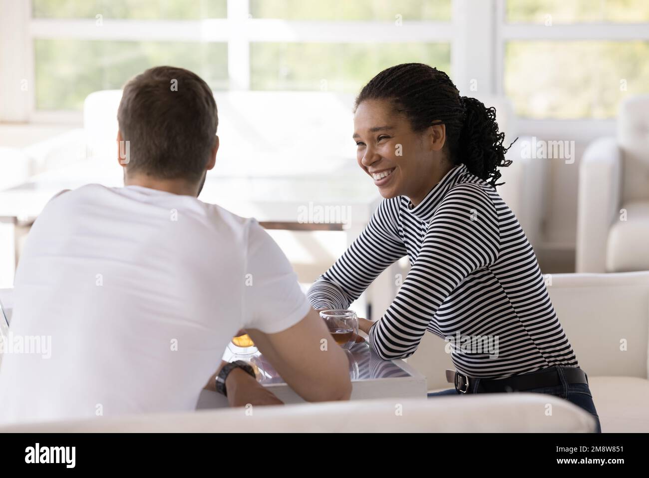 Jeune fille afro-américaine joyeuse parlant à un ami mâle caucasien Banque D'Images
