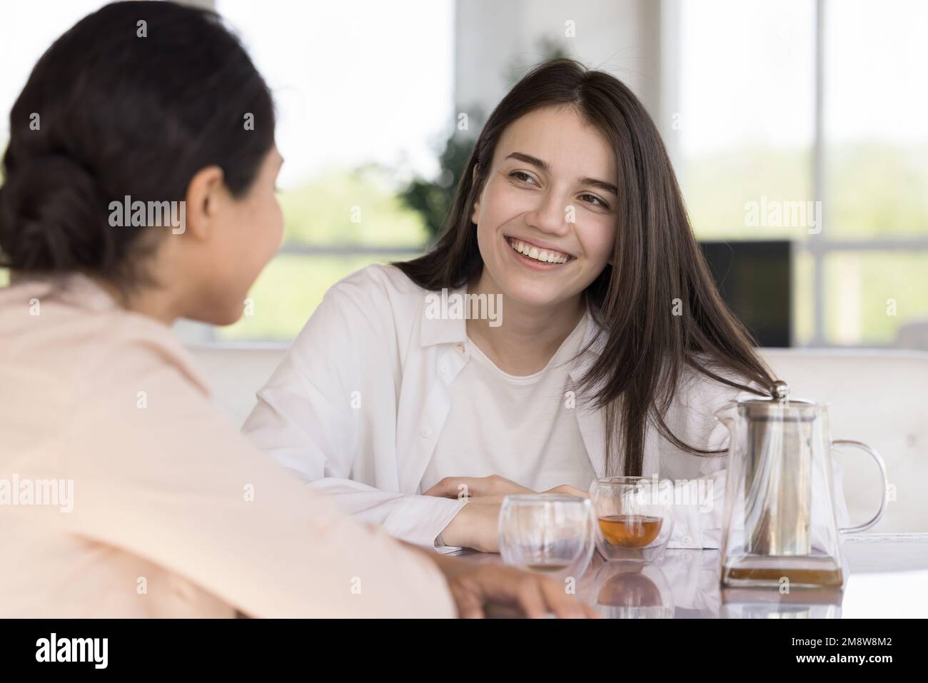 Joyeux amis féminins divers bavardant autour d'une tasse de thé Banque D'Images