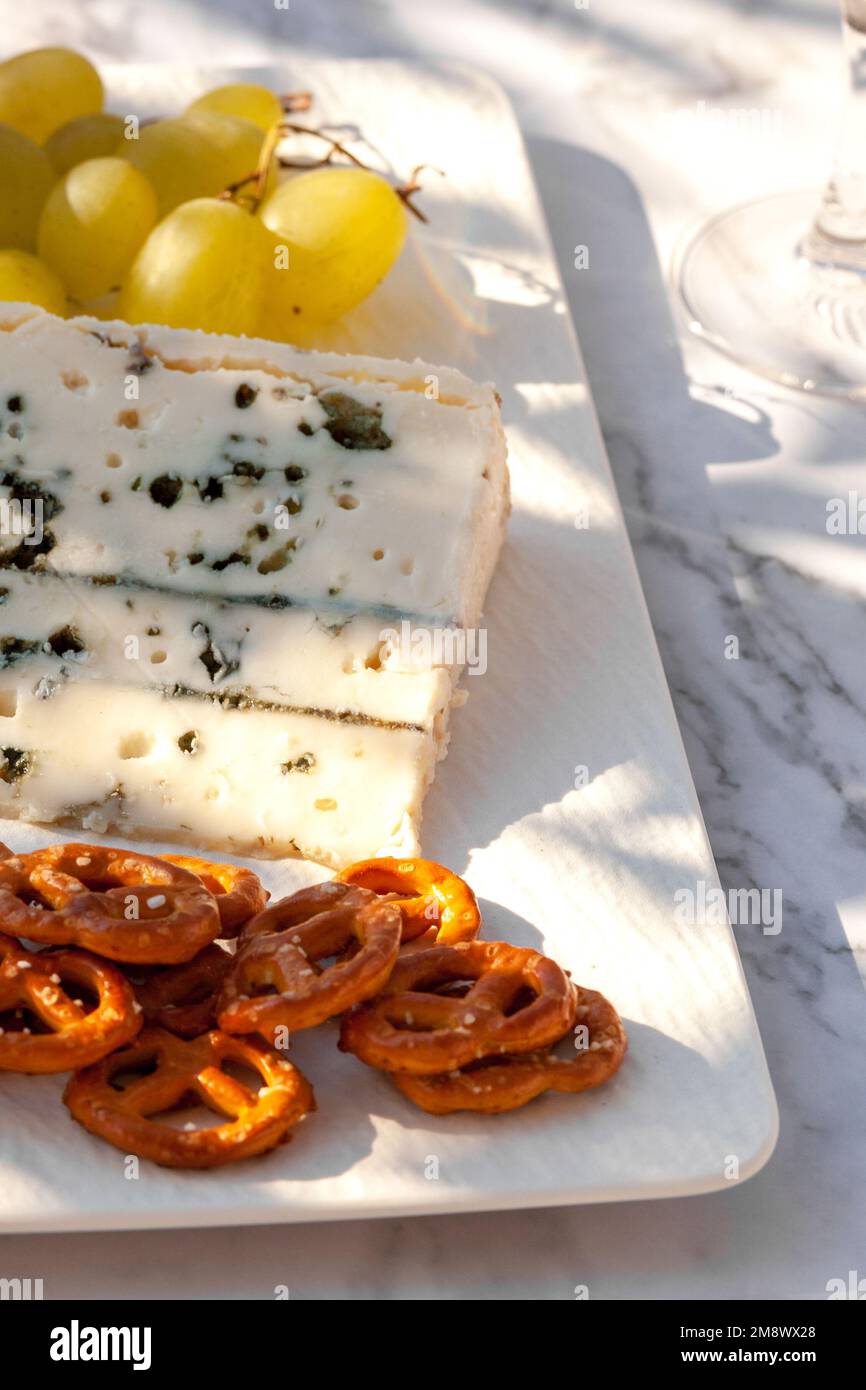 fromage roquefort servi avec des raisins verts et des en-cas à l'extérieur, lumière dure Banque D'Images