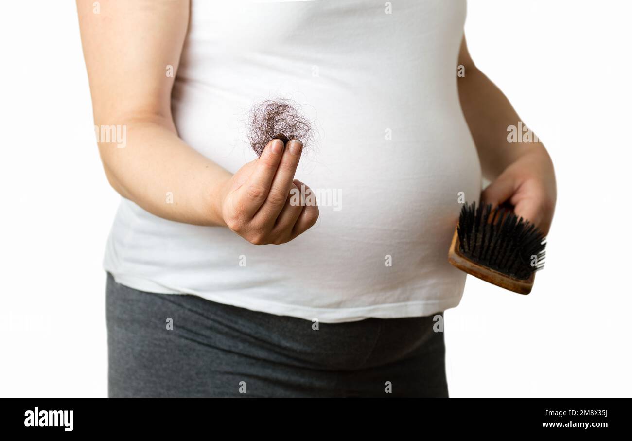 Femme enceinte montrant des cheveux tombés d'une main sur fond blanc Banque D'Images