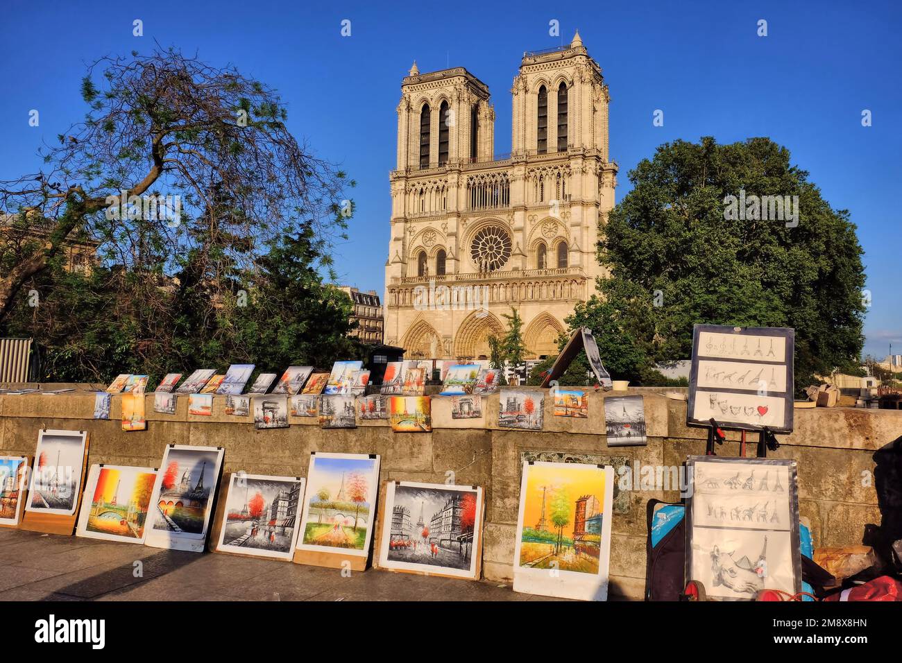 Paris: Art à vendre sur le petit Pont au-dessus de la Seine avec des tours de la Cathédrale notre Dame de l'or brillant peu avant le coucher du soleil sur l'Ile de la Cité, Paris, France Banque D'Images