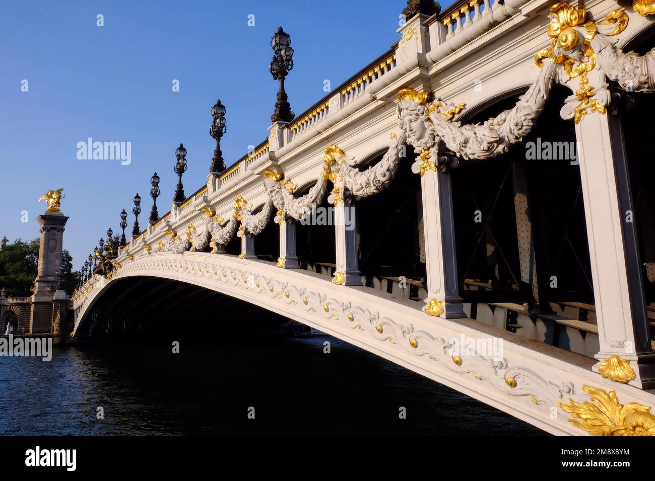 Paris : Pont Alexandre III pont sur la Seine éblouissant blanc contre ciel bleu peu avant le coucher du soleil à Paris, France Banque D'Images