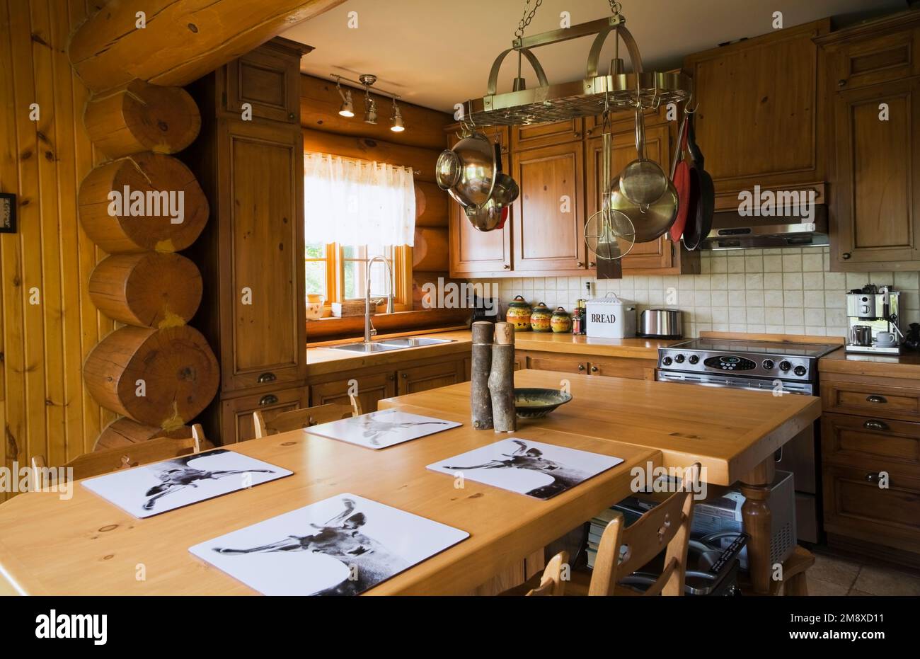 Armoires en bois de pin, table à manger et îlot dans la cuisine à l'intérieur de la maison en rondins de style cottage scandinave. Banque D'Images