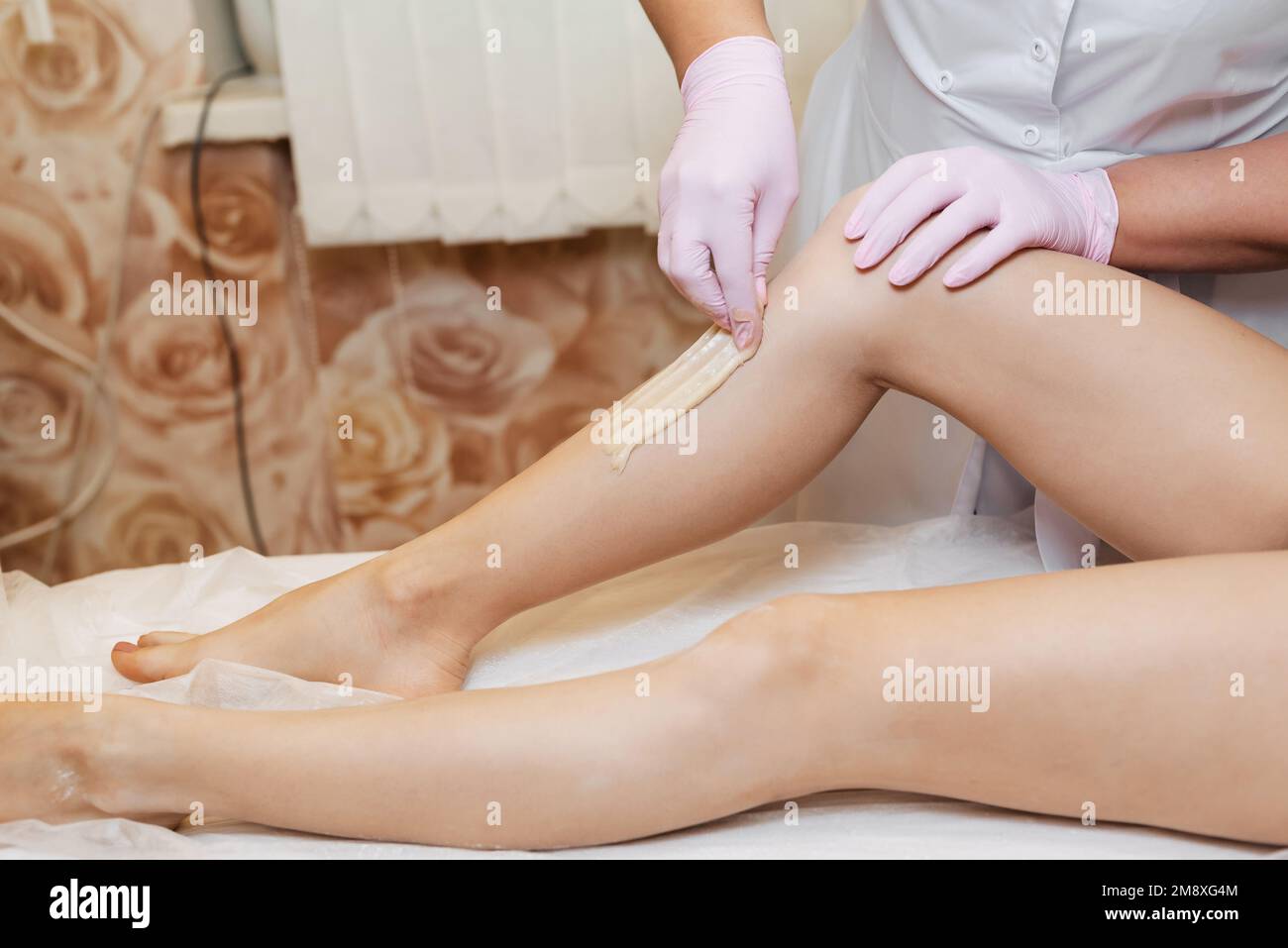 femme esthéticienne dans la procédure d'enlever les cheveux sur les jambes d'une fille avec l'épilation du sucre dans un salon de beauté moderne et les soins de la peau. Professionnel na Banque D'Images