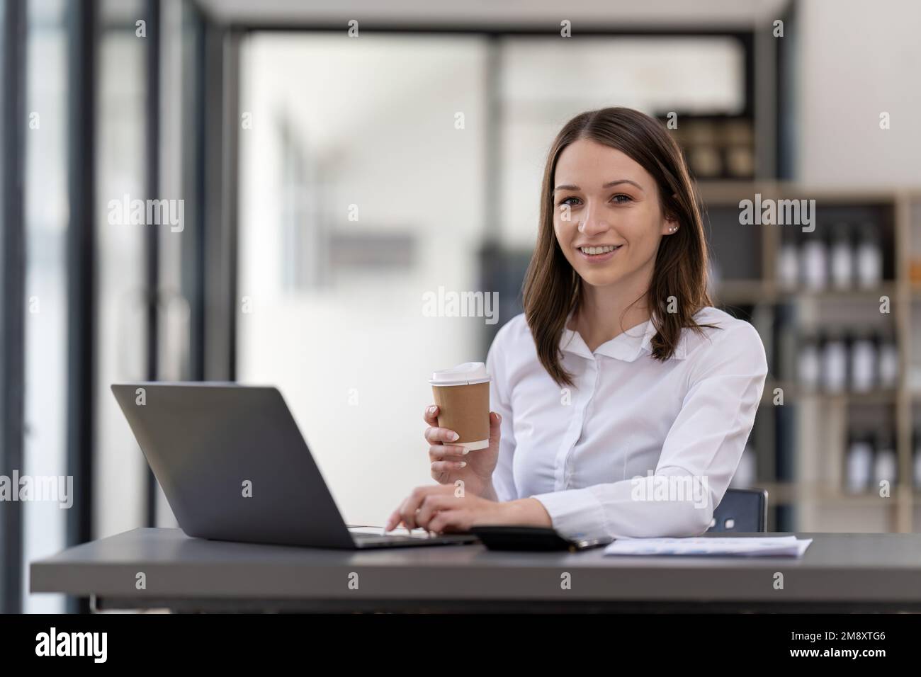 Portrait femme d'affaires confiante travaillant sur un ordinateur portable sur son lieu de travail dans un bureau moderne. Banque D'Images