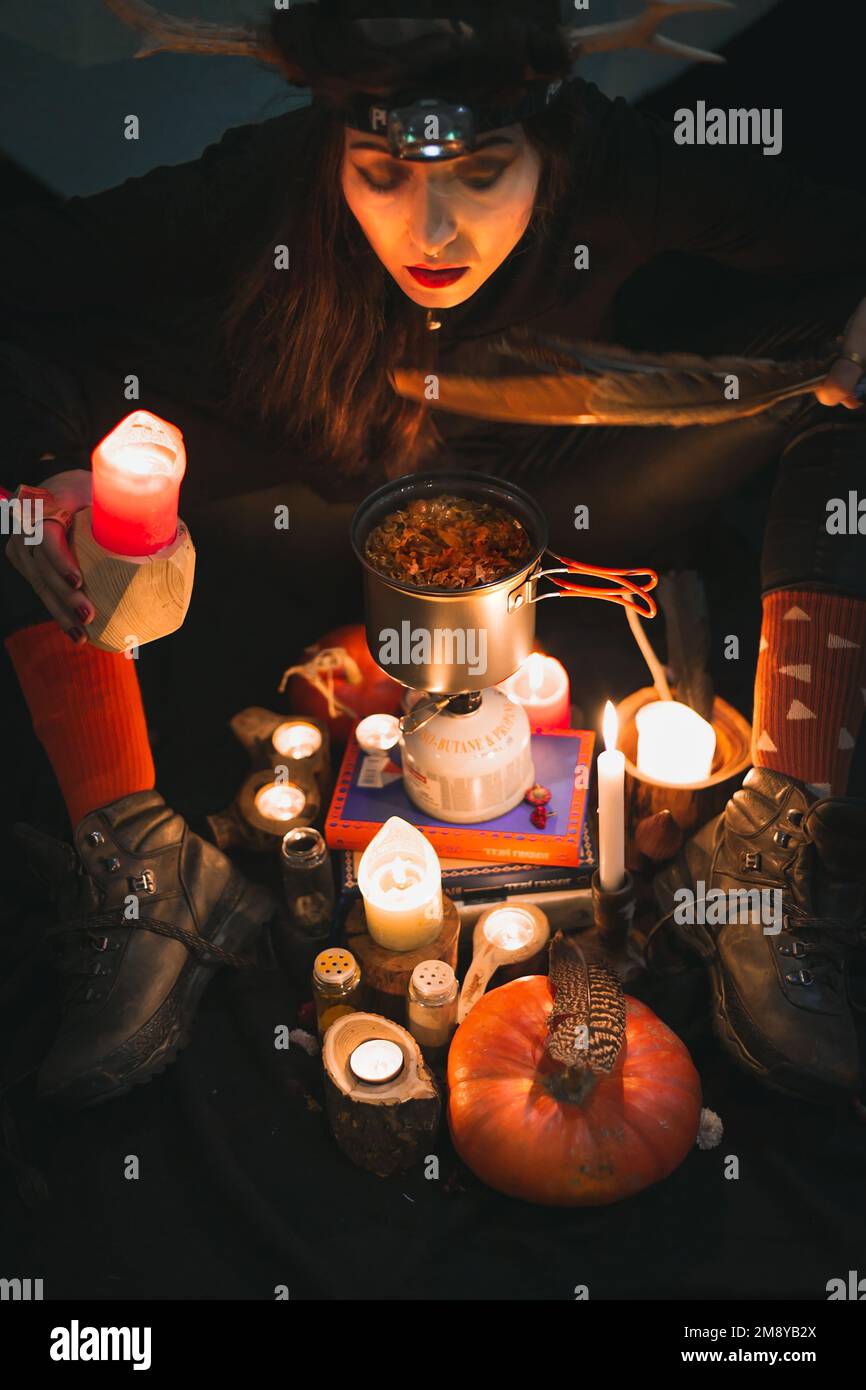 Gros plan femme shaman agitant avec la plume au-dessus de pot de brassage portrait image Banque D'Images