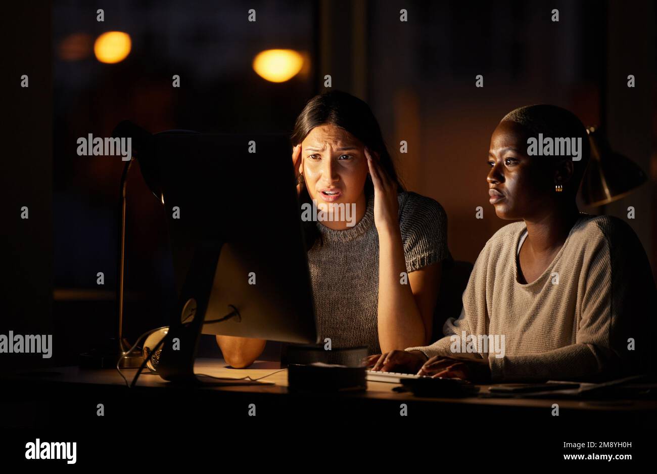 Je suis tellement troublée par ce qui se passe actuellement. deux femmes d'affaires ont l'air confuses lorsqu'elles travaillent ensemble la nuit sur un ordinateur dans un bureau. Banque D'Images