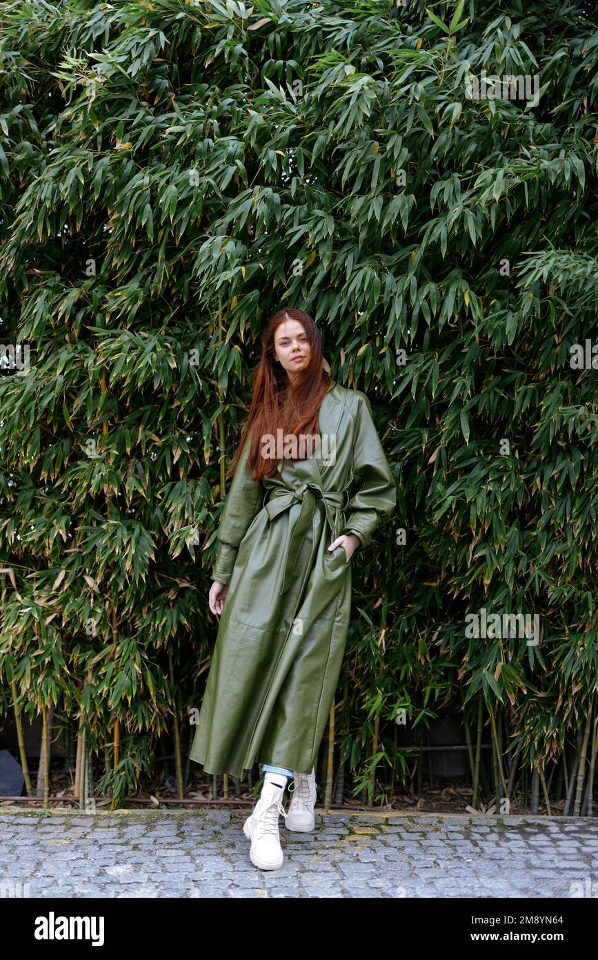 Femme influenceur dans des vêtements élégants et tendance pose sur toute la longueur avec un fond de bambous, le style de vie blogueur printemps Banque D'Images