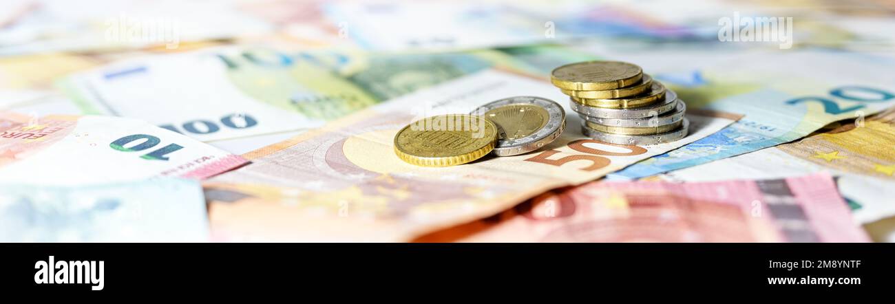 Pile de pièces de monnaie sur les billets en euros en format panoramique large, concept d'en-tête de site Web pour les affaires, la finance ou l'inflation, espace de copie, focus sélectionné, narr Banque D'Images