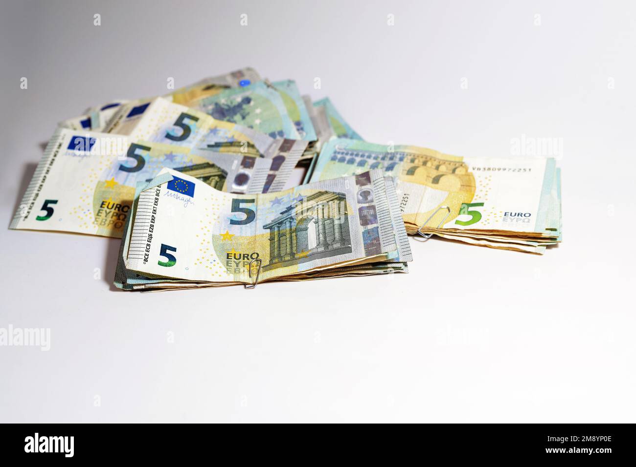 Piles de billets de cinq euros, la faible valeur collectée peut devenir beaucoup d'argent, concept pour les affaires, la finance ou l'inflation, fond gris clair, copie Banque D'Images