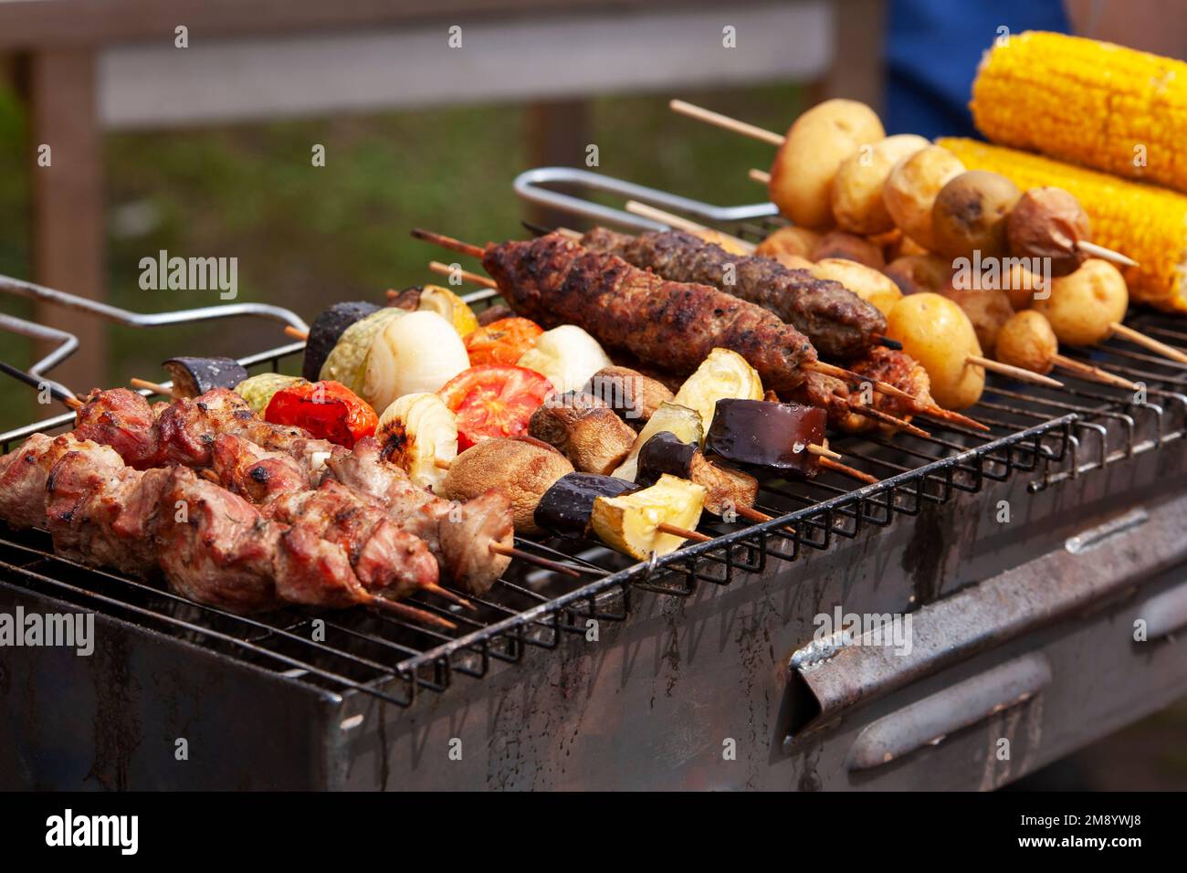 Assortiment de viandes grillées avec des légumes sur les charbons sur un barbecue Banque D'Images