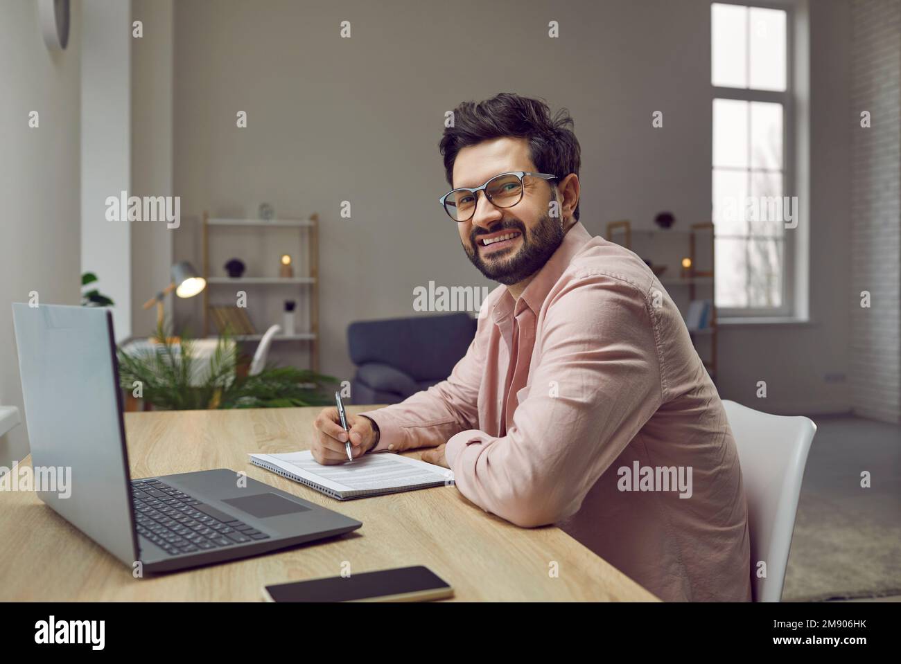 L'homme utilise un ordinateur portable, écrit, prend des notes, regarde un webinaire, s'entraîne ou participe à une leçon en ligne. Banque D'Images