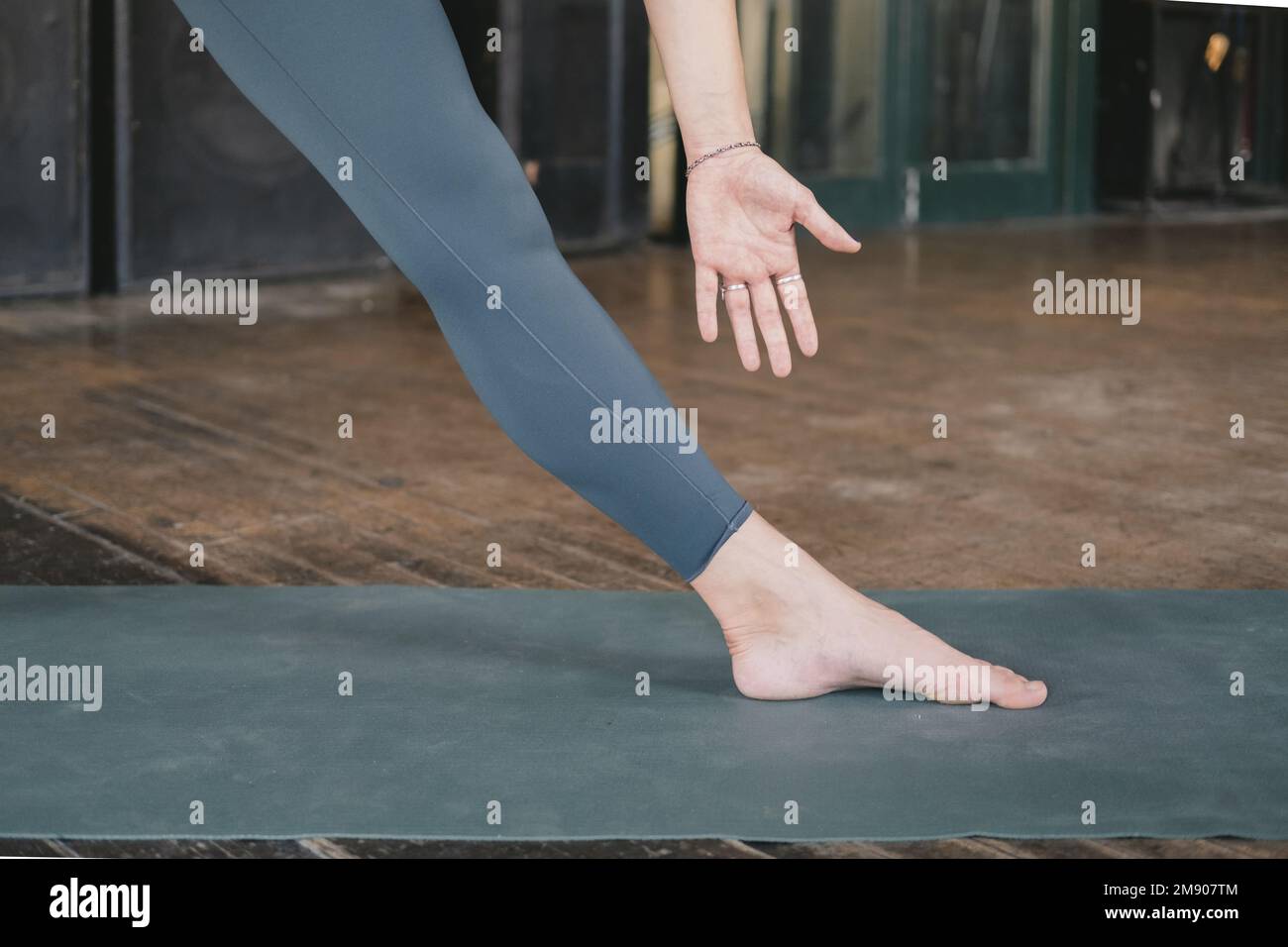 Photo en gros plan de la jambe et du bras de la jeune femme adulte non reconnaissable yogi et nouveau professeur faisant une posture triangulaire (Trikonasana) stretch, entraînement yoga Banque D'Images