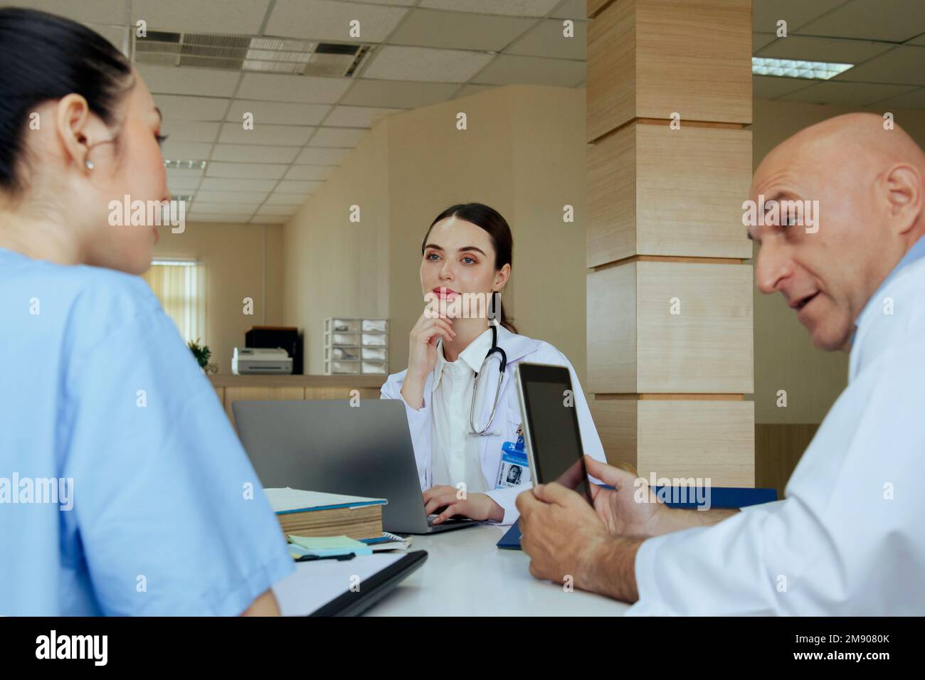 médecin d’équipe, infirmière et médecin de stage parlant et discutant du cas du patient en traitement chirurgical lorsqu’il est assis dans le bureau de la salle de réunion de hos Banque D'Images