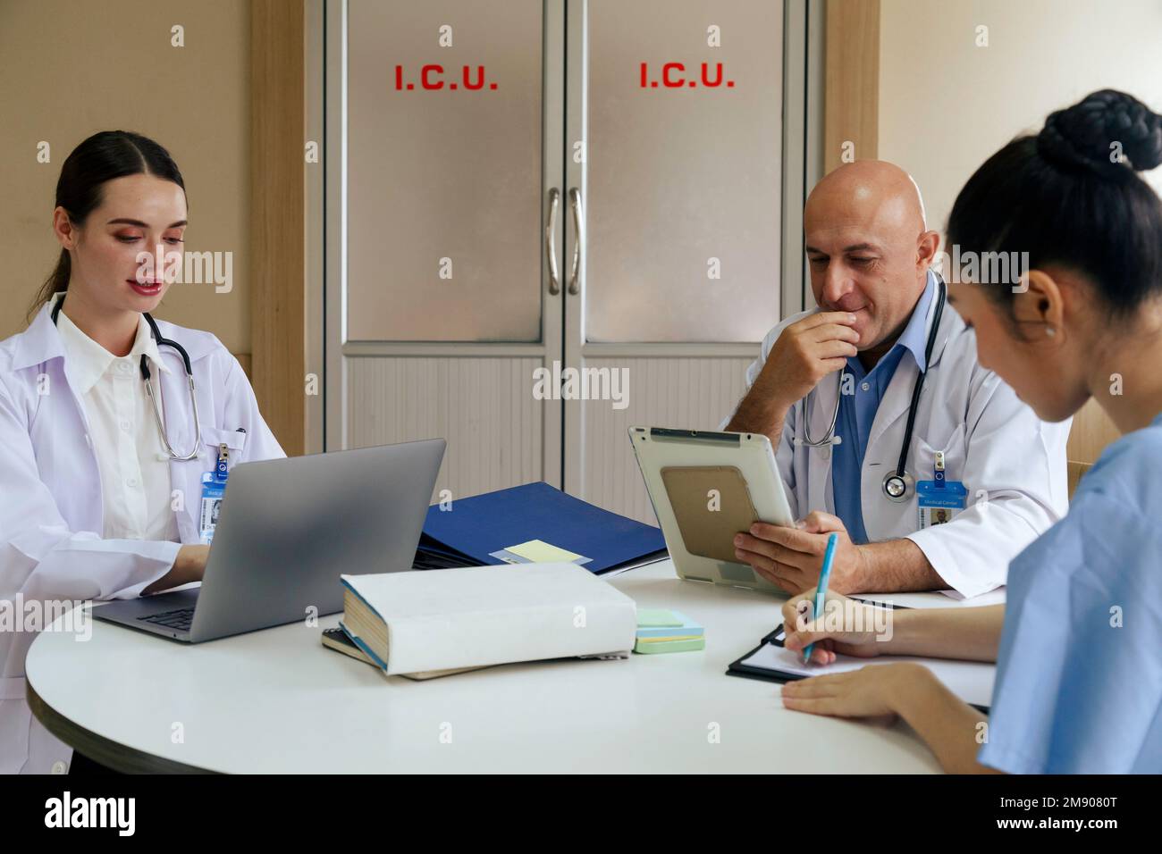 médecin d’équipe, infirmière et médecin de stage parlant et discutant du cas du patient en traitement chirurgical lorsqu’il est assis dans le bureau de la salle de réunion de hos Banque D'Images