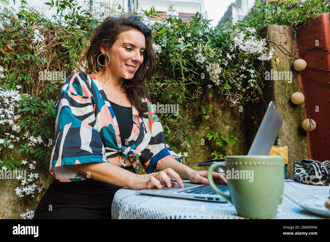 Heureuse excitée femme d'adulte caucasien regardant un ordinateur portable, surfer sur Internet, vérifier les e-mails et les notifications, travailler assis sur la terrasse, avec un c Banque D'Images