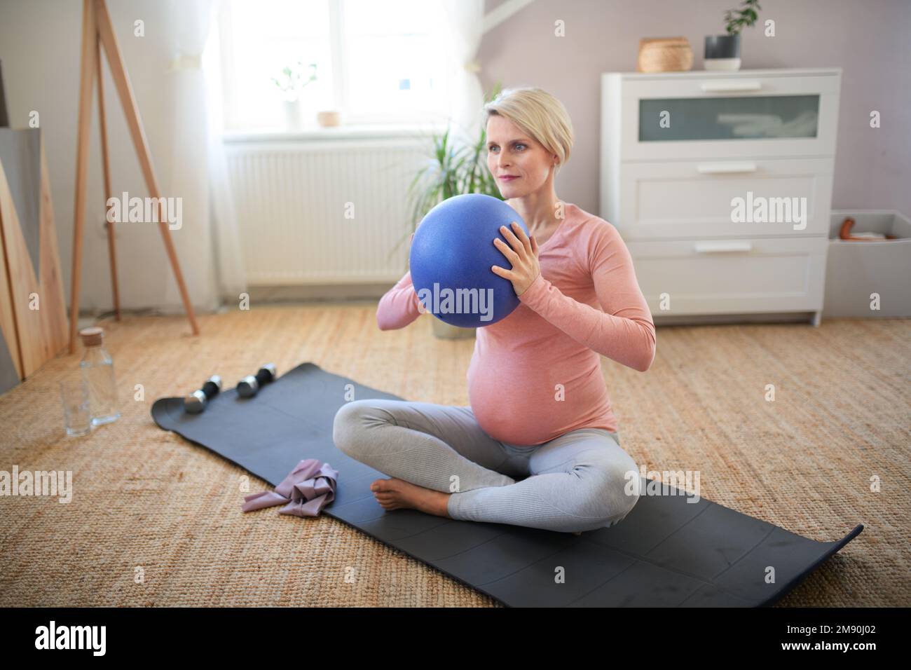 Femme enceinte faisant des exercices avec le ballon dans son appartement. Banque D'Images
