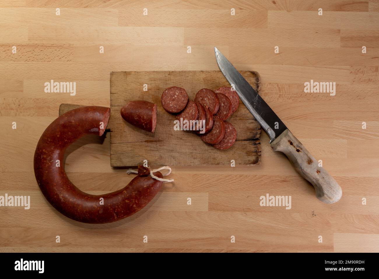 Couteau et saucisse en tranches sur planche à découper en bois dans la vue de dessus. Banque D'Images