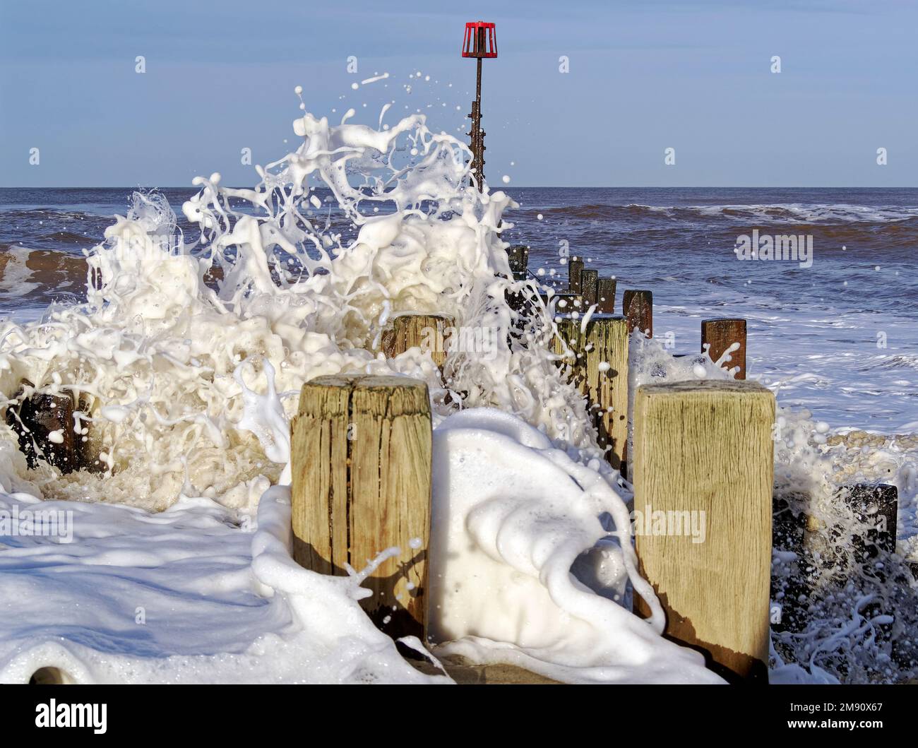 De grandes vagues se brisant sur des groynes en bois sur la plage de Walcott, dans le nord du Norfolk après une tempête qui s'apaise Banque D'Images