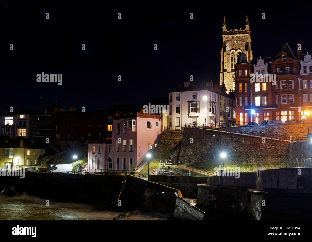 En regardant vers l'église Cromer et les rues des marins, Cromer Pier dans le nord de Norfolk la nuit, lors d'une soirée d'automne froide avec une lueur chaleureuse provenant de bâtiments éclairés. Banque D'Images