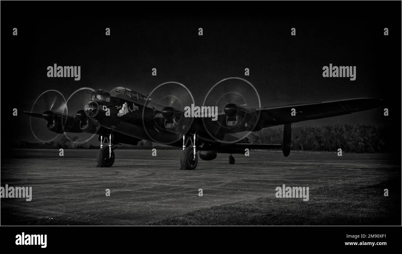 Image monochrome du bombardier AVRO Lancaster 'Just Jane', actuellement en cours de restauration au Lincolnshire Aviation Heritage Centre avec des moteurs fonctionnant après la tombée de la nuit. Banque D'Images