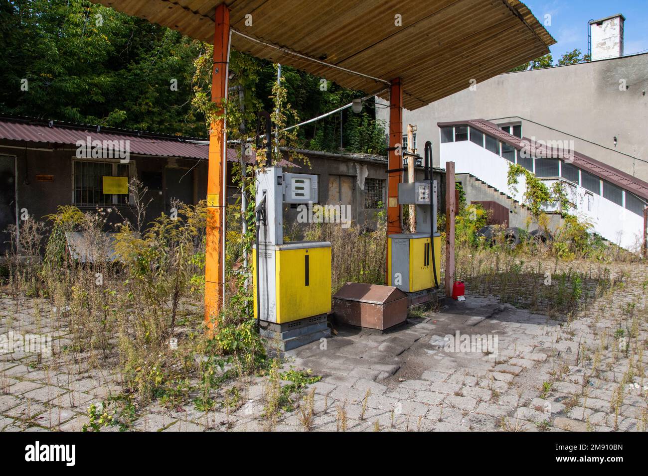 Une ancienne station de gaz rouillé et des distributeurs abandonnés et surcultivés avec de la végétation par une journée ensoleillée. Été. Banque D'Images