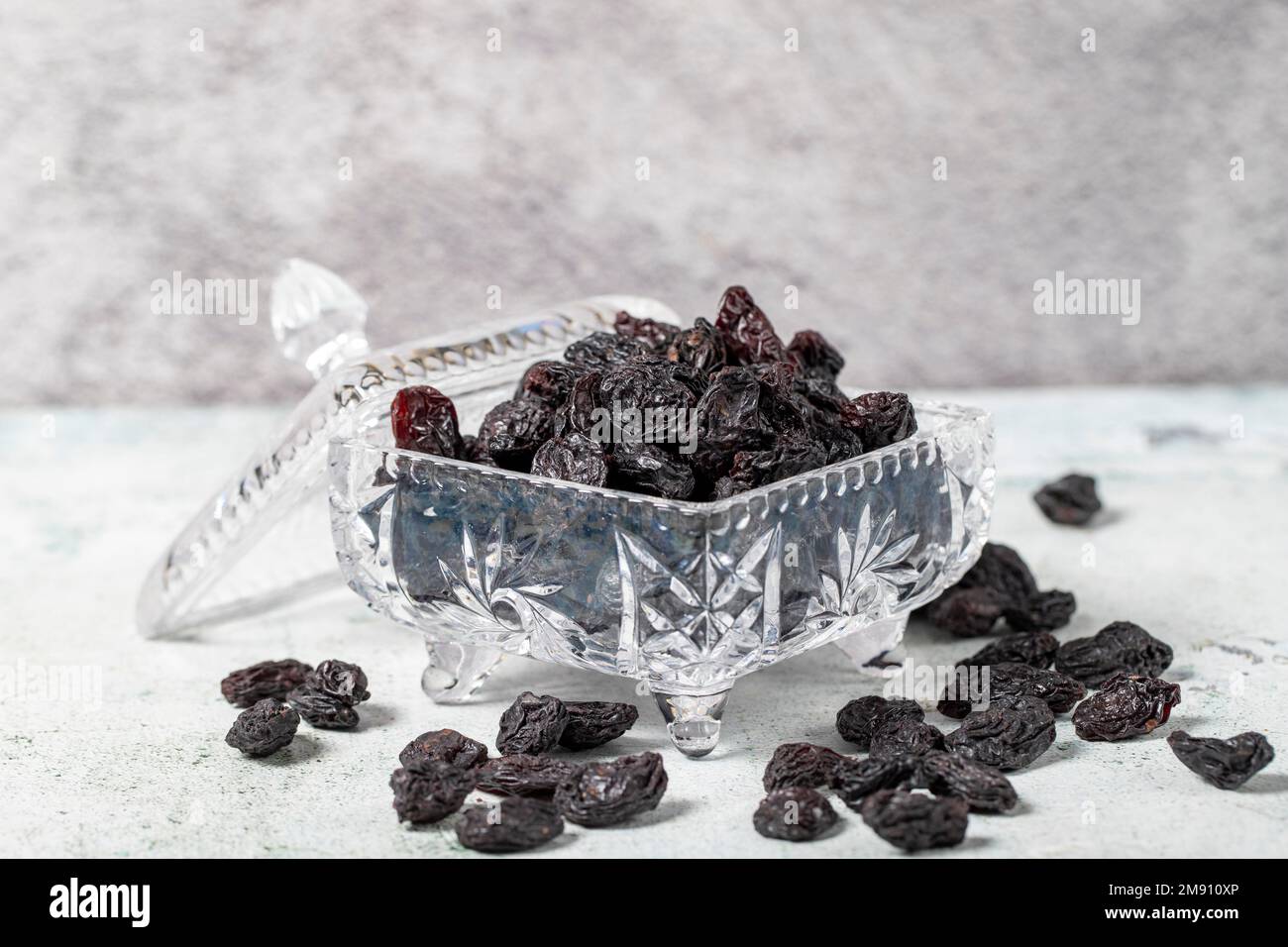 Raisins noirs séchés sur fond de pierre. Raisins secs dans un bol en verre. Variétés de noix. Une alimentation saine. gros plan Banque D'Images
