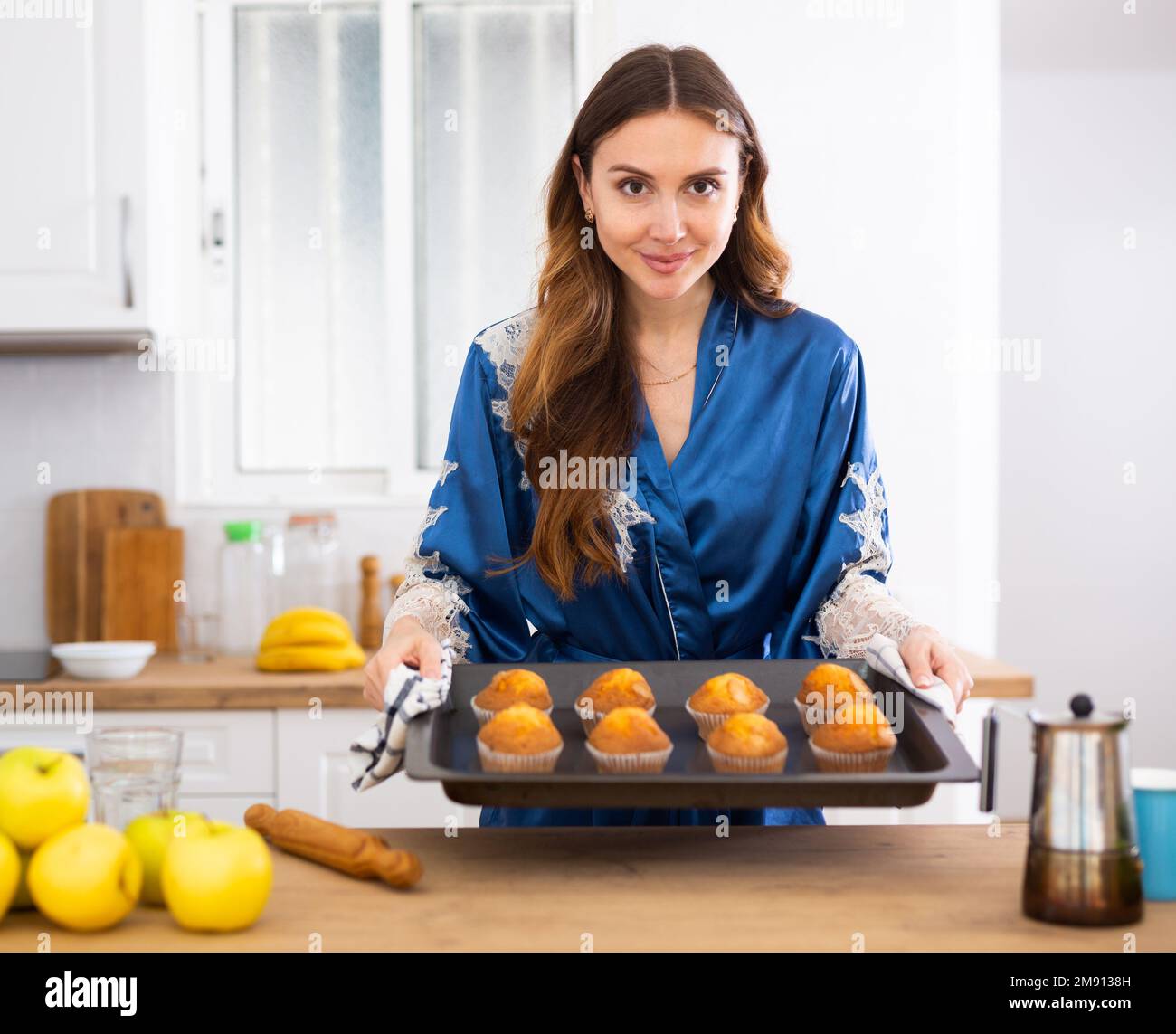 Femme en maison tenant une plaque de cuisson avec des petits gâteaux sucrés cuits dans la cuisine Banque D'Images