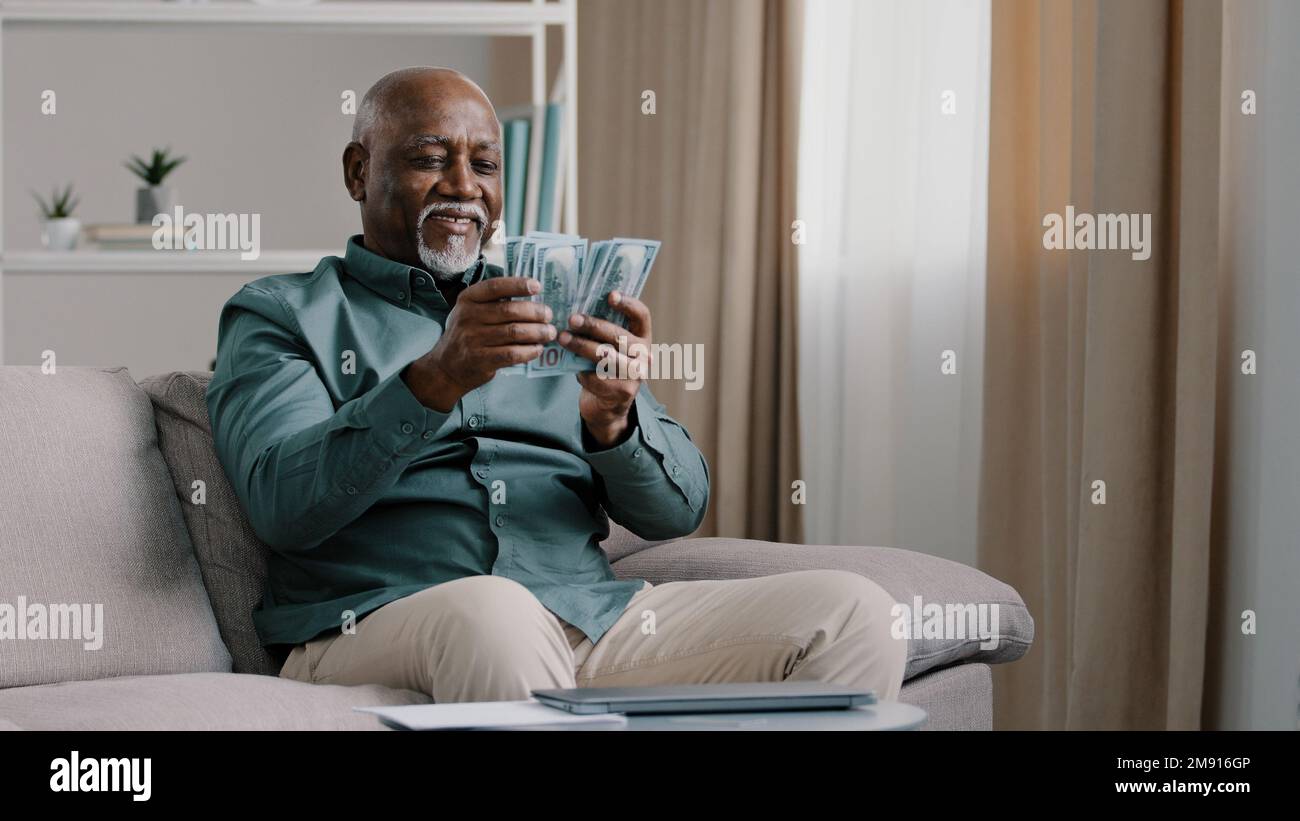 Joyeux vieil homme âgé africain américain en surpoids, âgé et mature, satisfait des économies financières sur le salaire à la maison. Loterie en ligne gagnante Banque D'Images