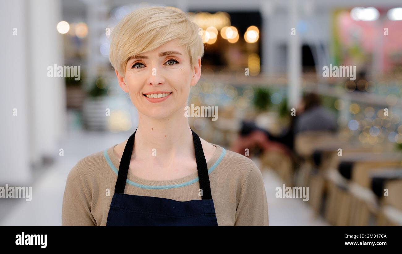 Gros plan femme Barista adulte. Portrait serveuse caucasienne femme d'âge moyen blonde avec une coupe courte sourire en dents de souris en regardant l'appareil photo sourire. Vue de dessus Banque D'Images