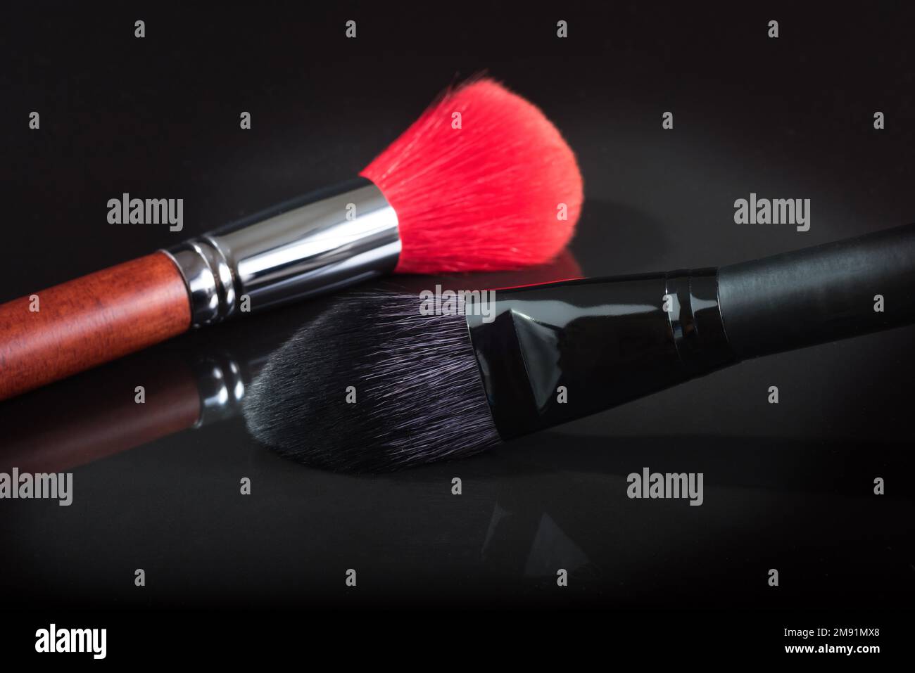 Pinceau noir et rouge pour un maquillage sur fond noir. gros plan Banque D'Images