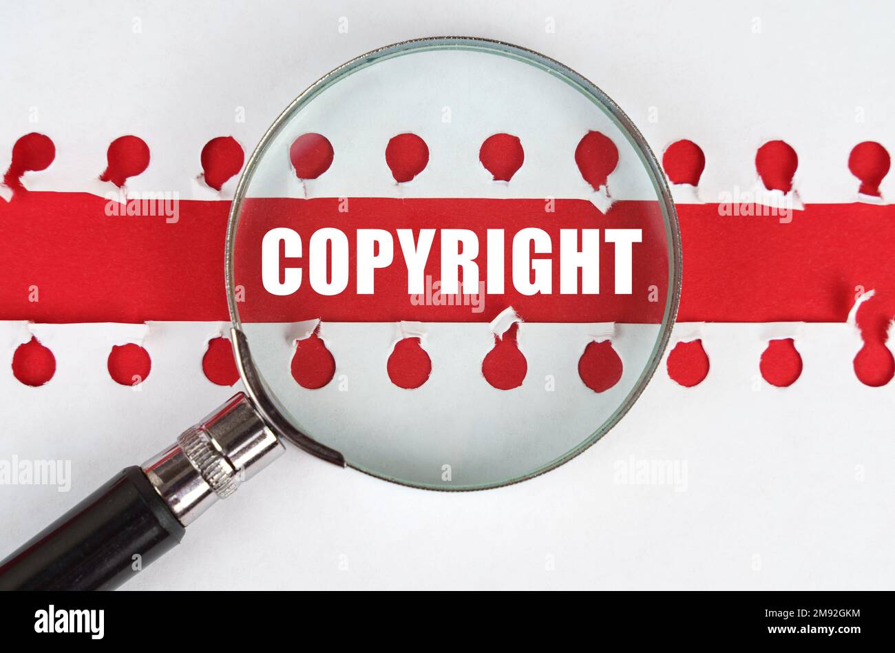 Entre deux feuilles d'un bloc-notes sur une bande rouge avec l'inscription - Copyright, il y a une loupe. Banque D'Images