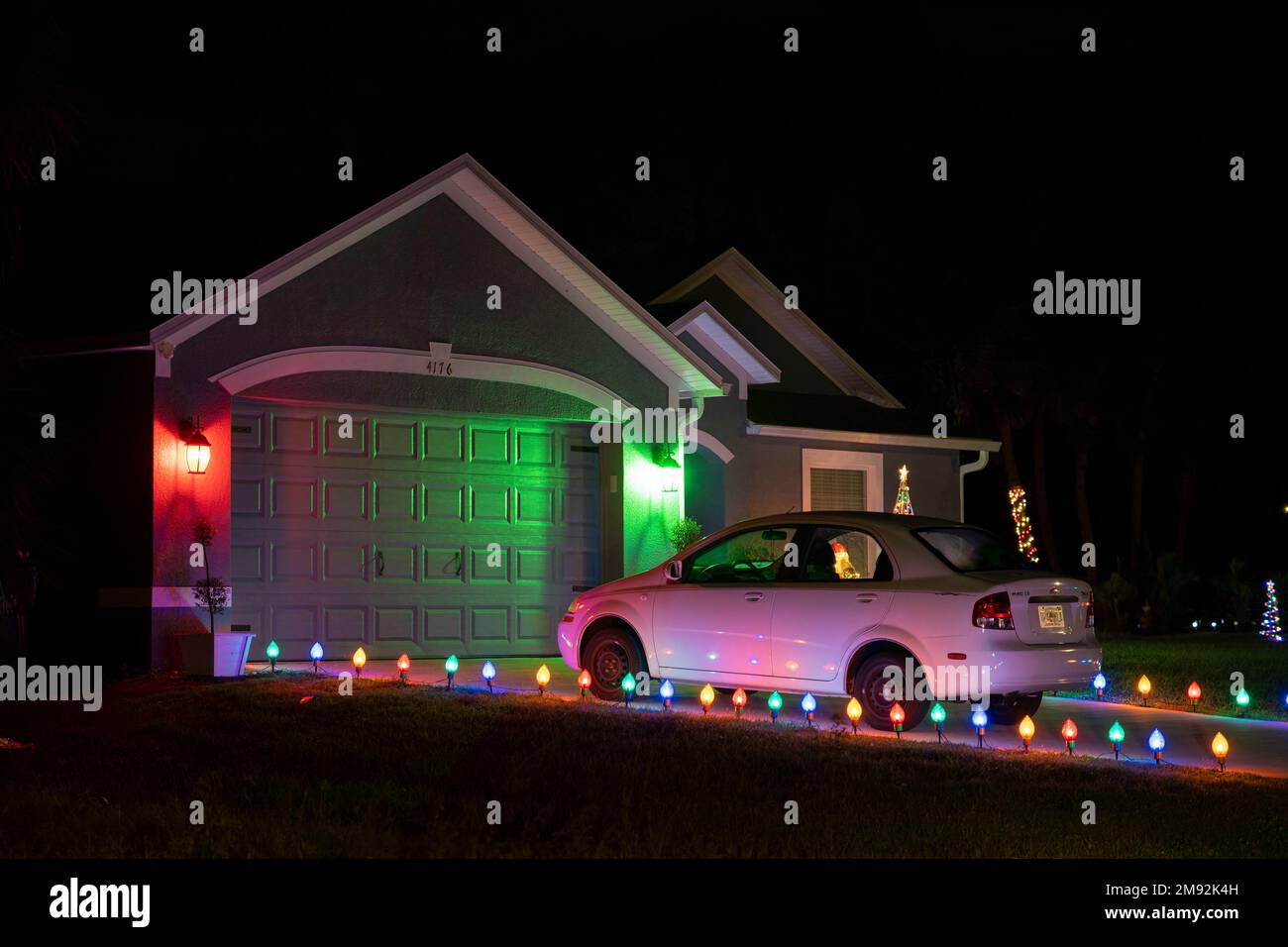 Décorations de noël illuminées de couleurs vives sur l'allée de cour avant du garage de la maison familiale de floride. Décor extérieur pour les vacances d'hiver Banque D'Images